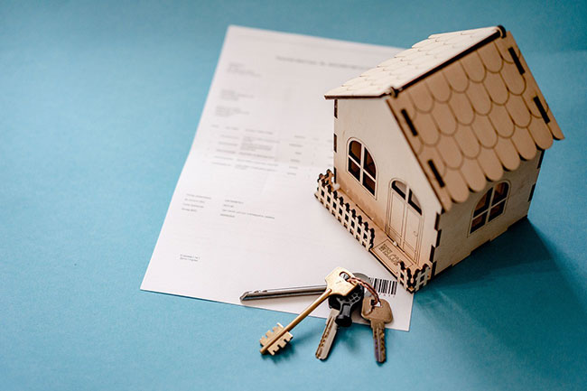 A picture of keys, a house model, and paper, representing the change Karam took from law to real estate.